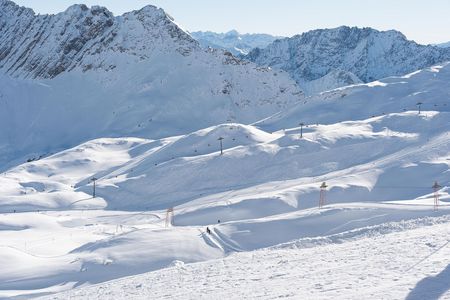 Skipiste mit Schnee und felsigen Bergen im Hintergrund
