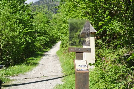 Schotterweg im Grünen mit Infotafel und historischem Bild am Rand der Alten Ettaler Bergstraße