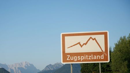 Blauer Himmel und im Vordergrund Hinweisschild zum Zugspitzland